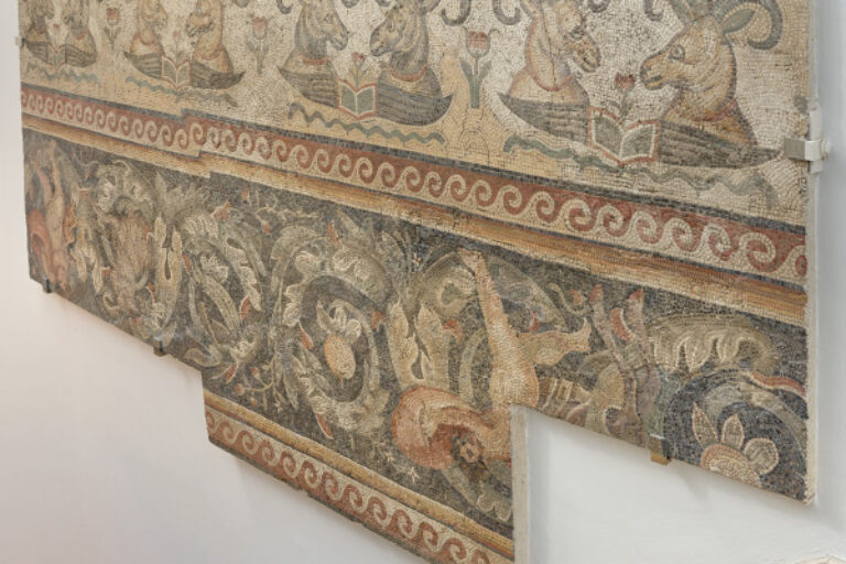 Border fragment of floor mosaic depicting rams’ heads over open wings