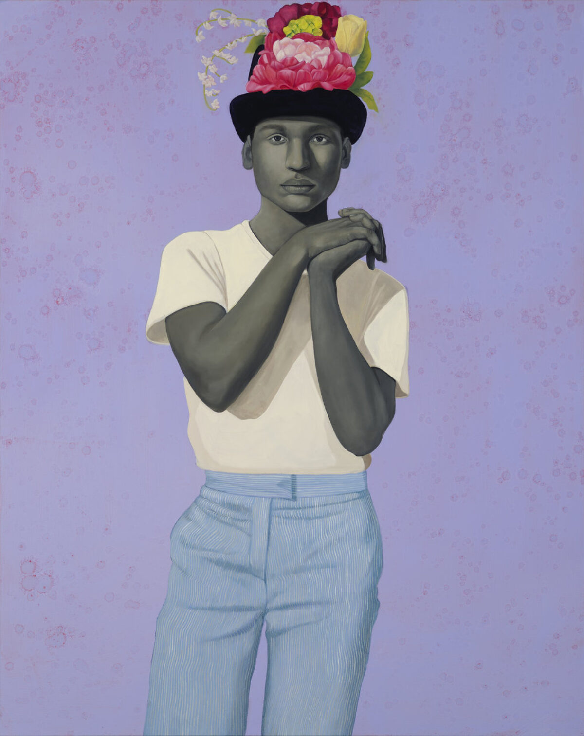 A painting depicts a person with grayscale skin, wearing a white t-shirt and light blue pinstriped pants. They stand with hands clasped, looking forward, and wear a black hat adorned with vibrant pink, yellow, and white flowers. The background is a speckled lavender.