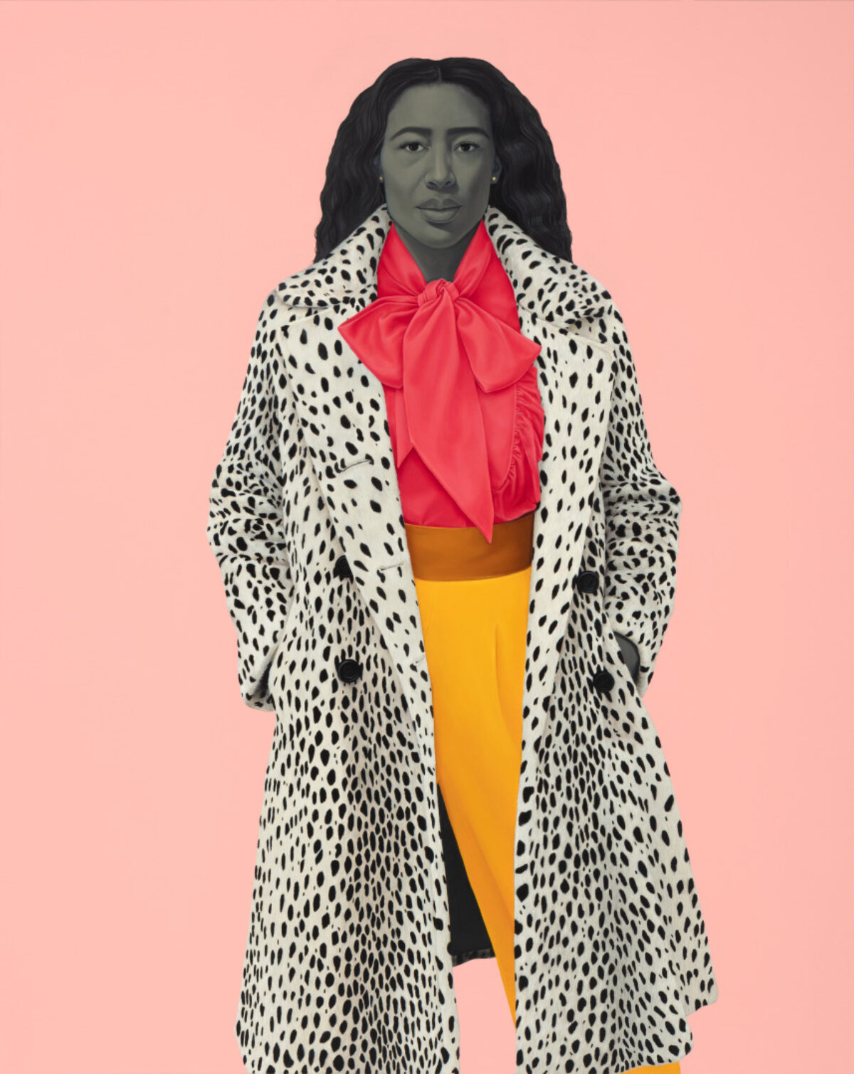 A person with in a white coat with black spots, a red bow blouse, and yellow pants stands against a solid light pink background. The person has dark, wavy hair and a gray-toned face, with hands in the coat pockets.